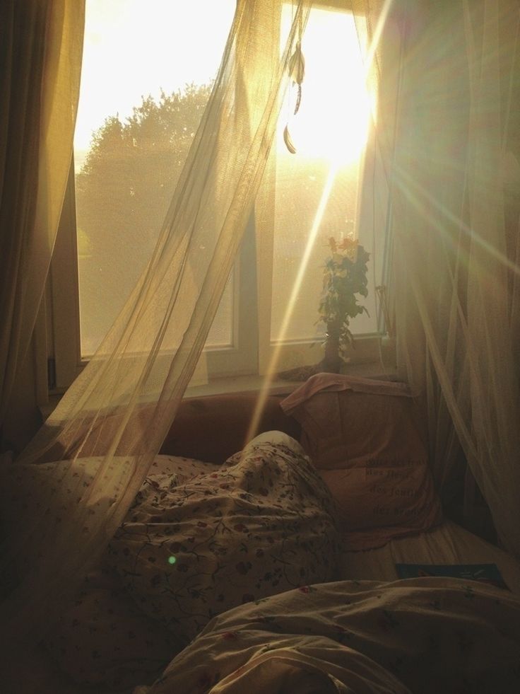 the sun shines brightly through sheer curtains on a bed in front of a window