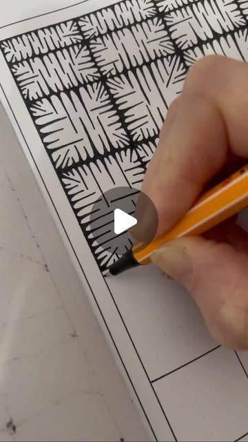 a person holding a pencil in their left hand and drawing on paper with black ink