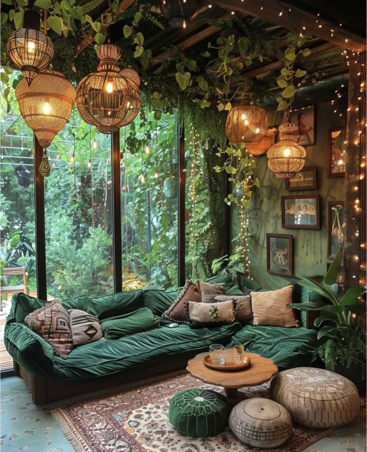 a living room filled with lots of green furniture and hanging lights on the wall above it