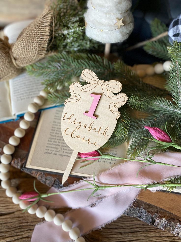 a wooden sign sitting on top of a table next to some flowers and a book