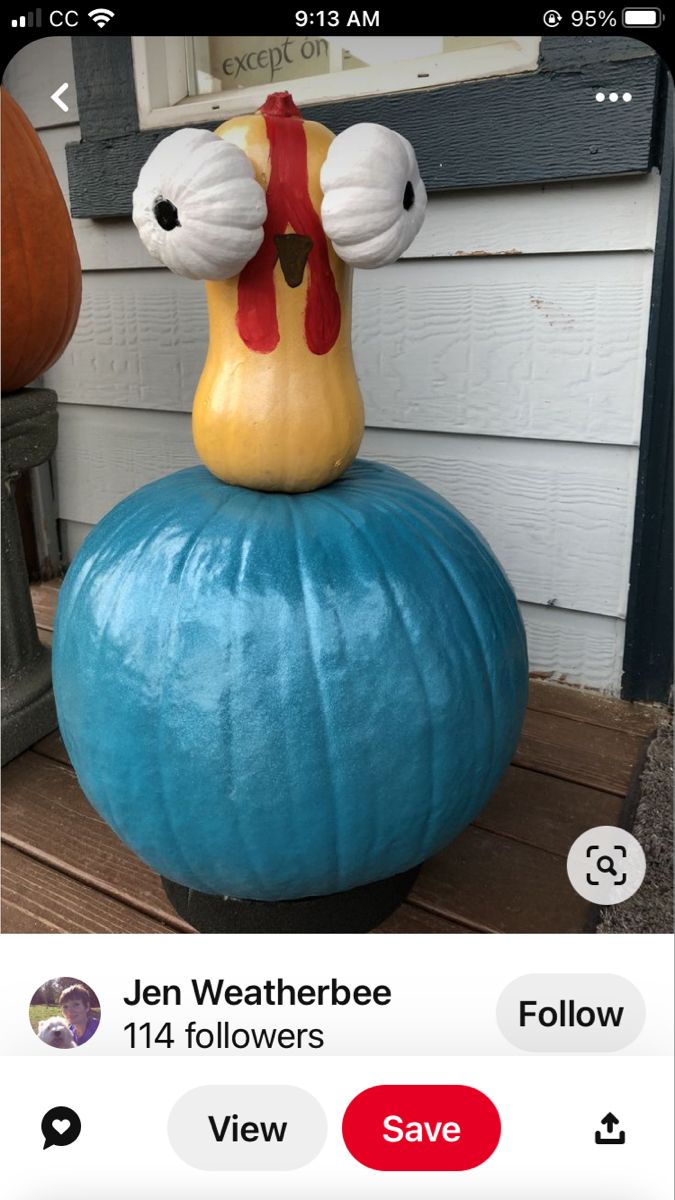 a fake chicken sitting on top of a blue pumpkin