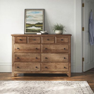 a wooden dresser sitting on top of a hard wood floor next to a white door