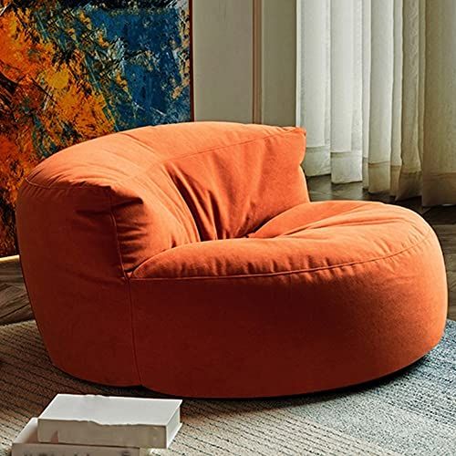 an orange bean bag chair sitting on top of a rug in front of a painting