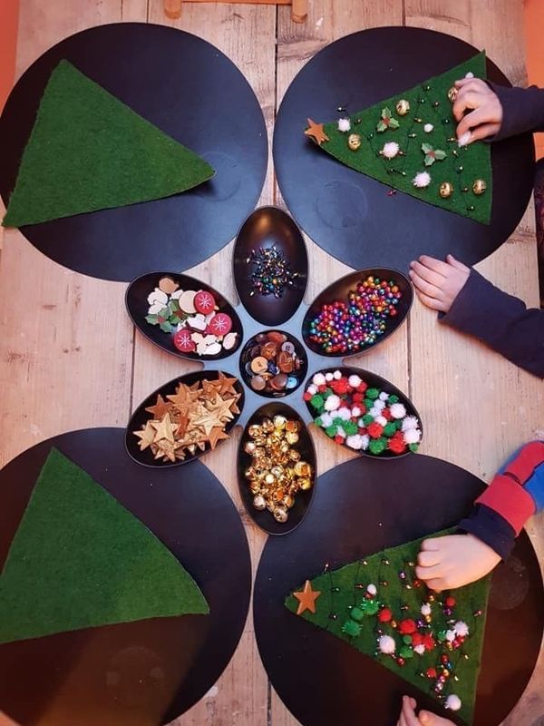 several children are making christmas trees out of paper plates on the table with their hands