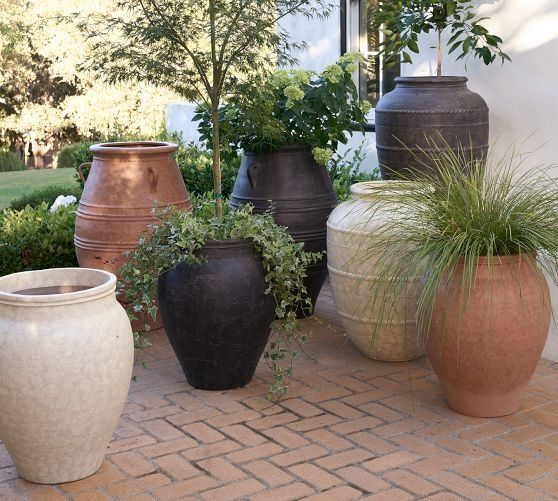 several large vases are lined up on the brick walkway in front of a house