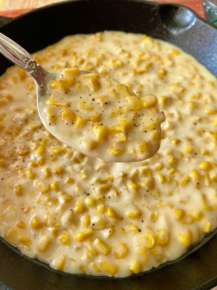 a skillet filled with corn on top of a table