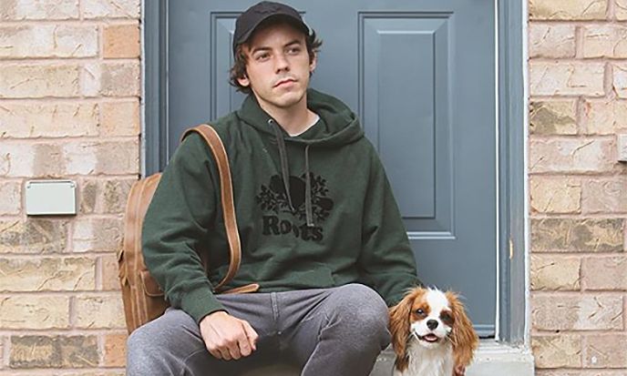 a young man sitting on the steps with his dog