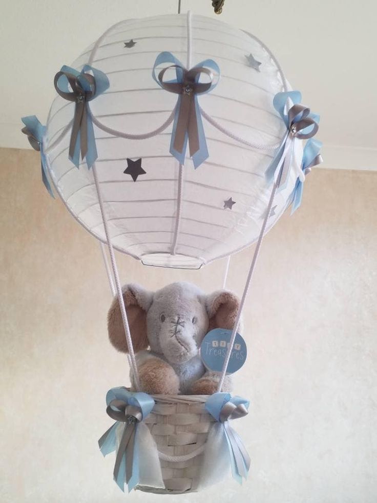 a stuffed animal in a basket hanging from the ceiling with ribbons on it's sides