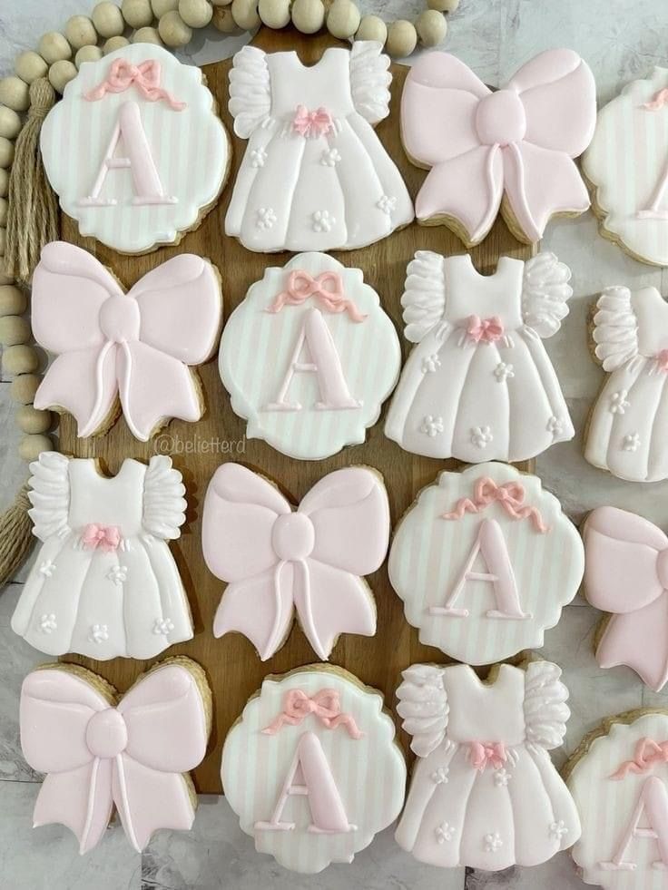 decorated cookies in the shape of baby's clothes and bows are displayed on a table