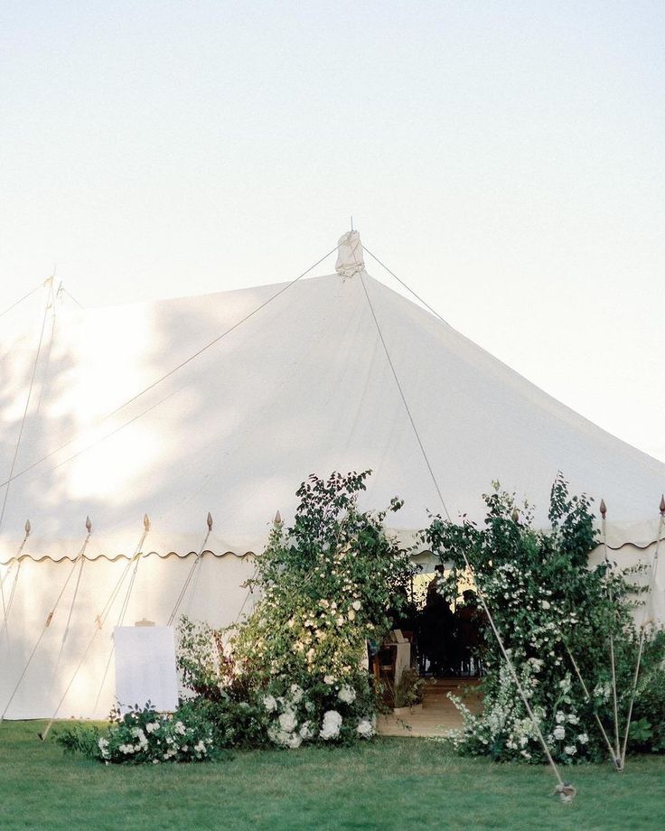 a large white tent with flowers and greenery