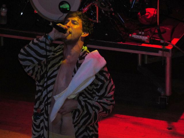 a man standing in front of a microphone on top of a red light filled stage