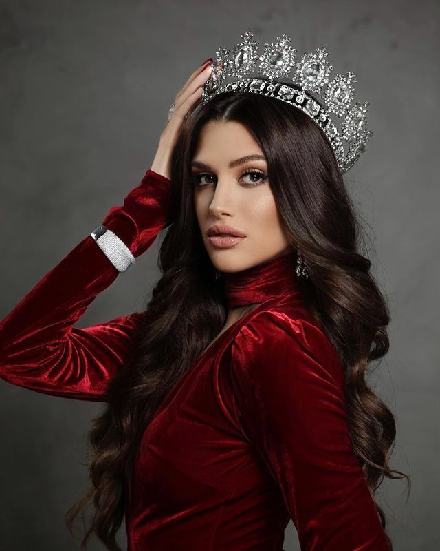 a beautiful woman wearing a tiara and posing for a photo with her hands on her head