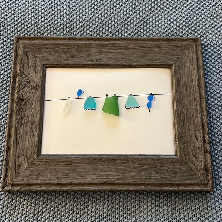 three little birds are hanging on a line with clothes pins in the shadow box frame