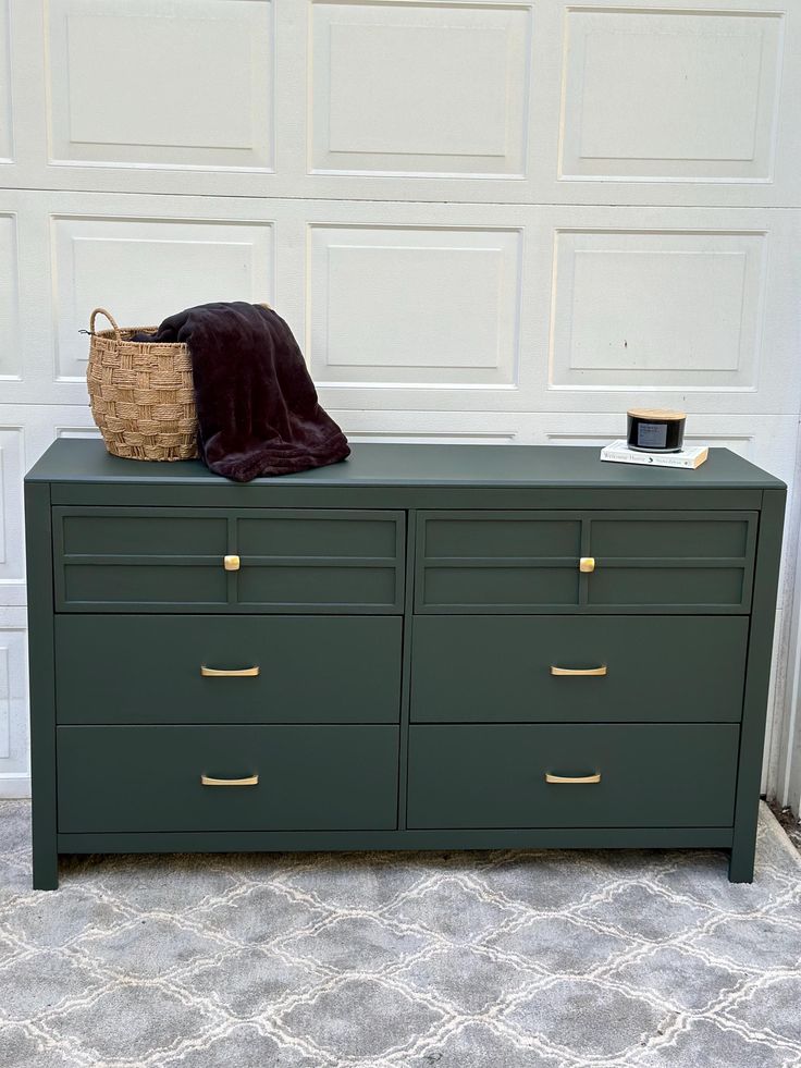 a green dresser with a brown blanket on top and a basket sitting on top of it