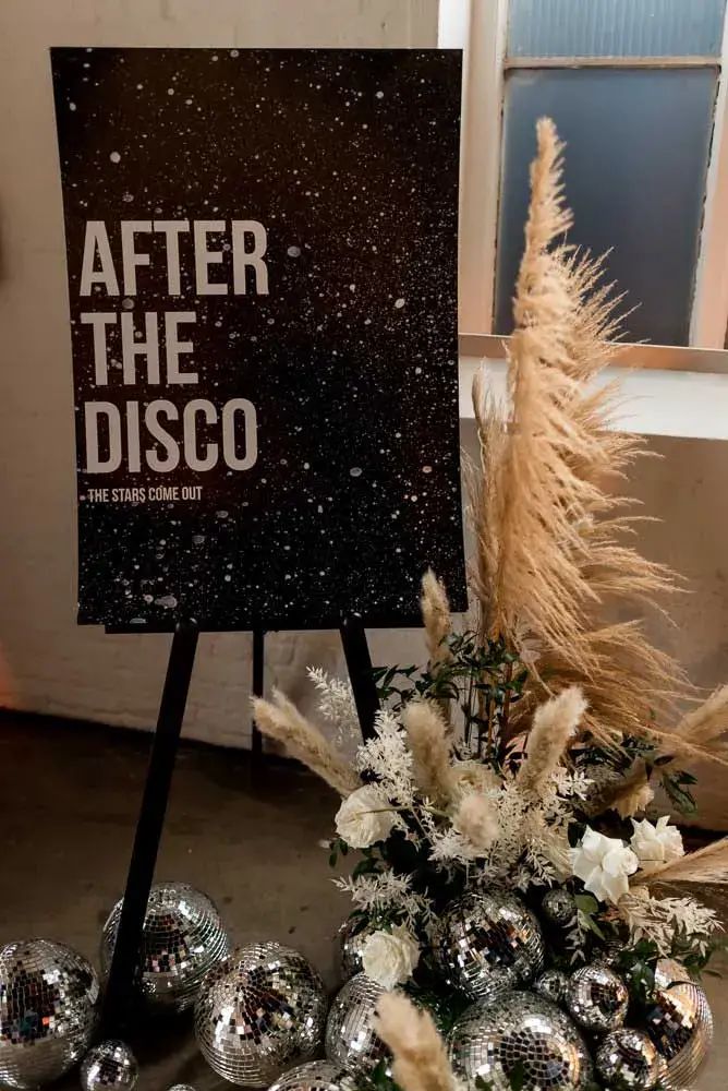 a sign that says after the disco next to some silver balls and pamy plants