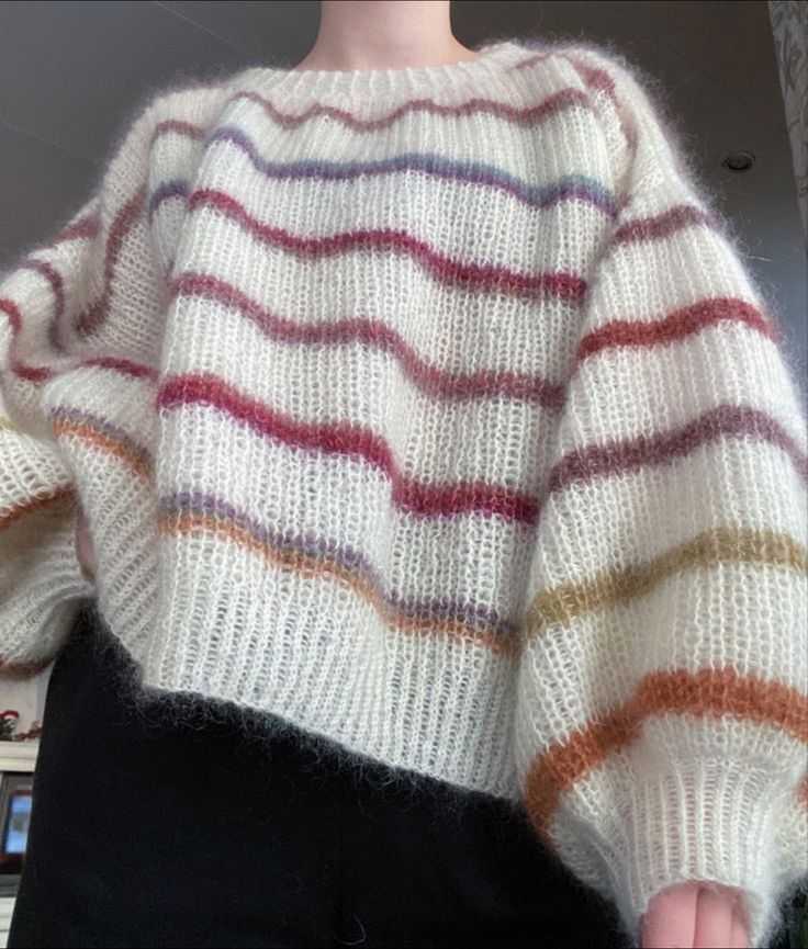 a woman is wearing a sweater with multicolored stripes