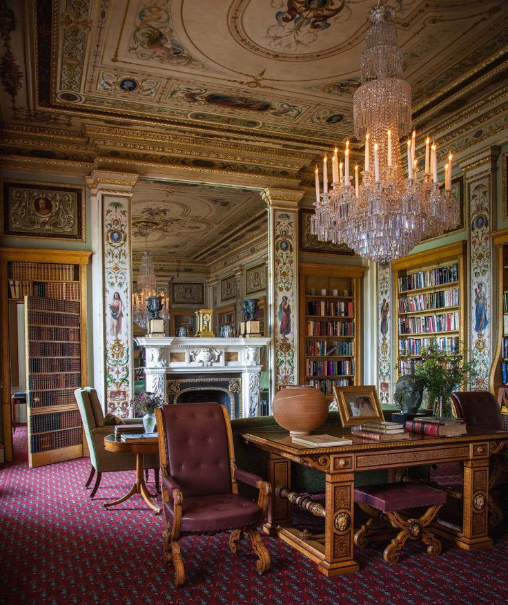 an ornate room with chandelier, chairs and table in front of bookshelves