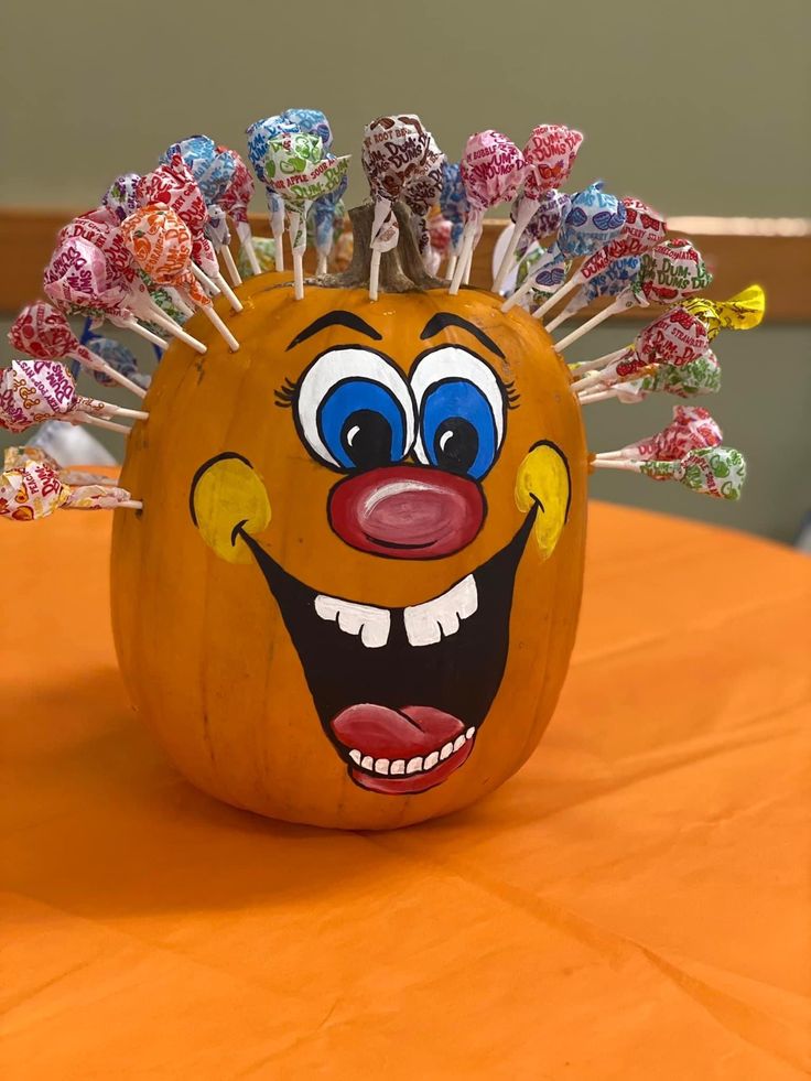 a pumpkin decorated with candy sticks and an evil clown's face on top of it