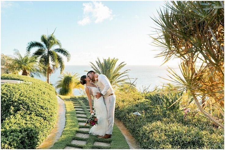 a bride and groom kissing in front of the ocean at their wedding venue by the beach