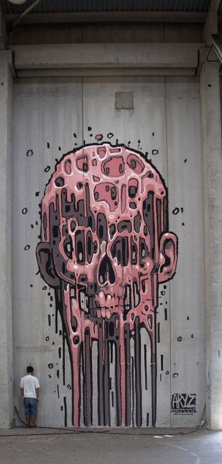 a man standing in front of a graffiti covered garage door with a pink skull painted on it