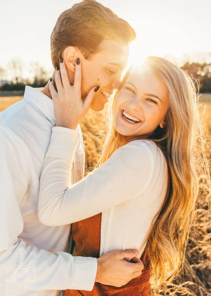 a man and woman standing in a field with the sun shining down on them smiling