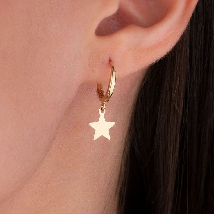 Our star charm earring is 14k solid gold and it has a star charm that dangles on it. It's an earring that looks beautiful on your all outfit. Thanks to its closure, our gold star hoop earring is comfortable enough to wear every day. If you are searching for a gift for your loved ones, this dangle star earring will be a perfect choice. It makes happy your loved ones on mother's day, birthdays, valentine's day, anniversaries, Christmas, or graduations. The gold star hoop earring's inner diameter i Yellow Gold Star Huggie Earrings For Gift, Star-shaped Earrings With Dangling Charms As Gift, Star-shaped Earrings With Dangling Charms For Gift, Gift Star Charm Dangle Huggie Earrings, Star Charm Dangle Huggie Earrings As Gift, Gift Dangle Huggie Earrings With Star Charm, Gift Huggie Earrings With Star Charm Dangle, Yellow Gold Huggie Earrings With Star Charm, Star-shaped Huggie Earrings As A Gift