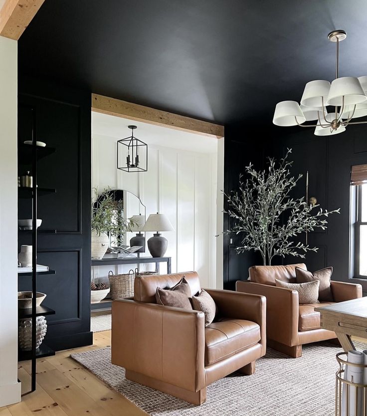 a living room with black walls and leather furniture