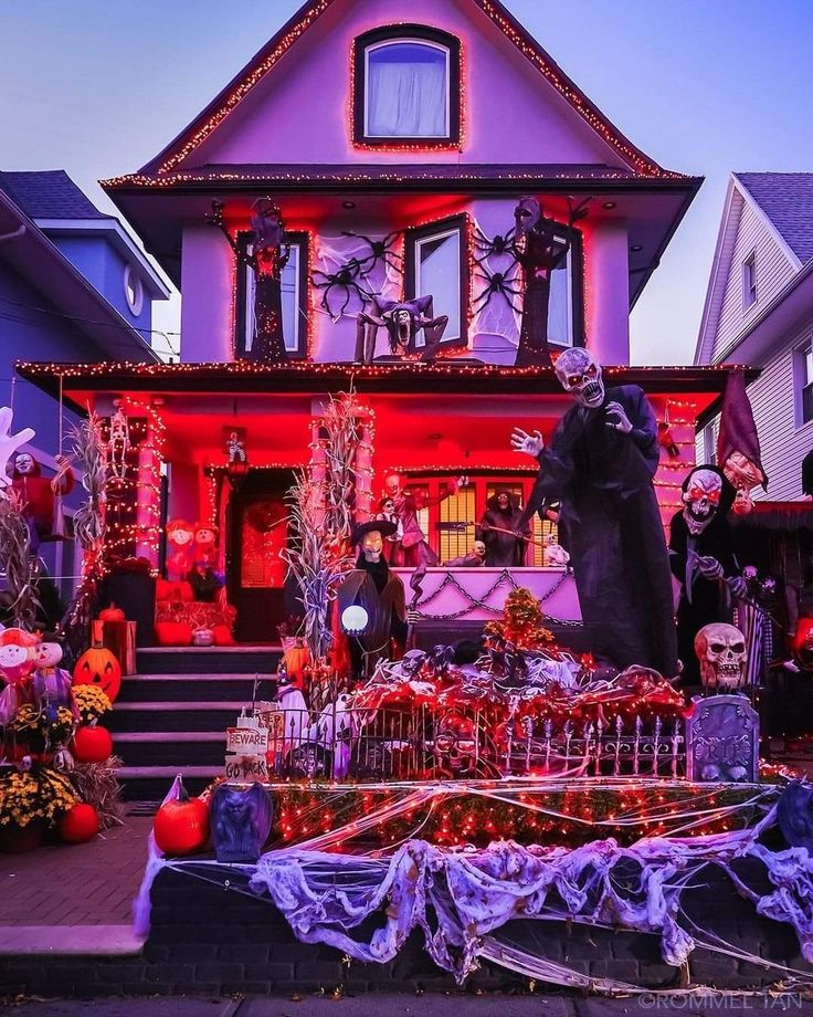 a house decorated for halloween with decorations and skeletons on the front porch, all dressed up