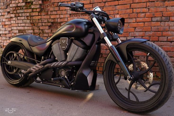 a black motorcycle parked next to a brick wall