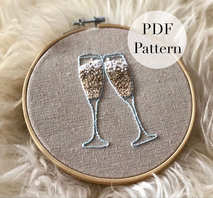 two glasses of champagne in the middle of a hand embroidery pattern on a white furnishing