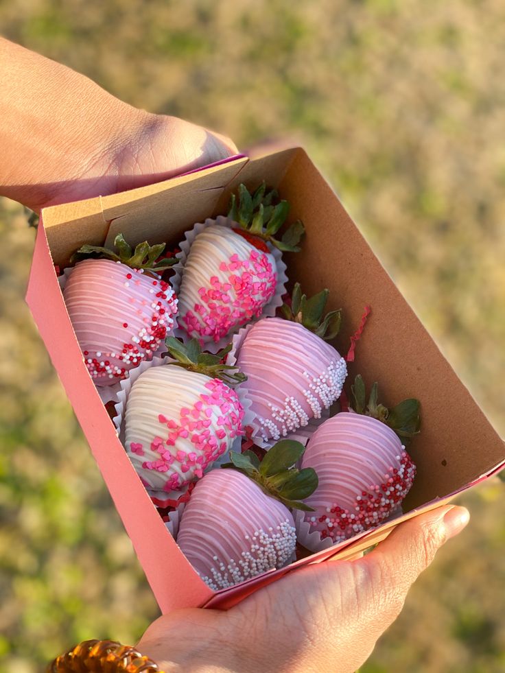 a person holding a box full of chocolate covered strawberries