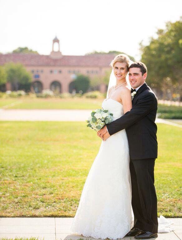 a bride and groom pose for a photo in front of the building at their wedding