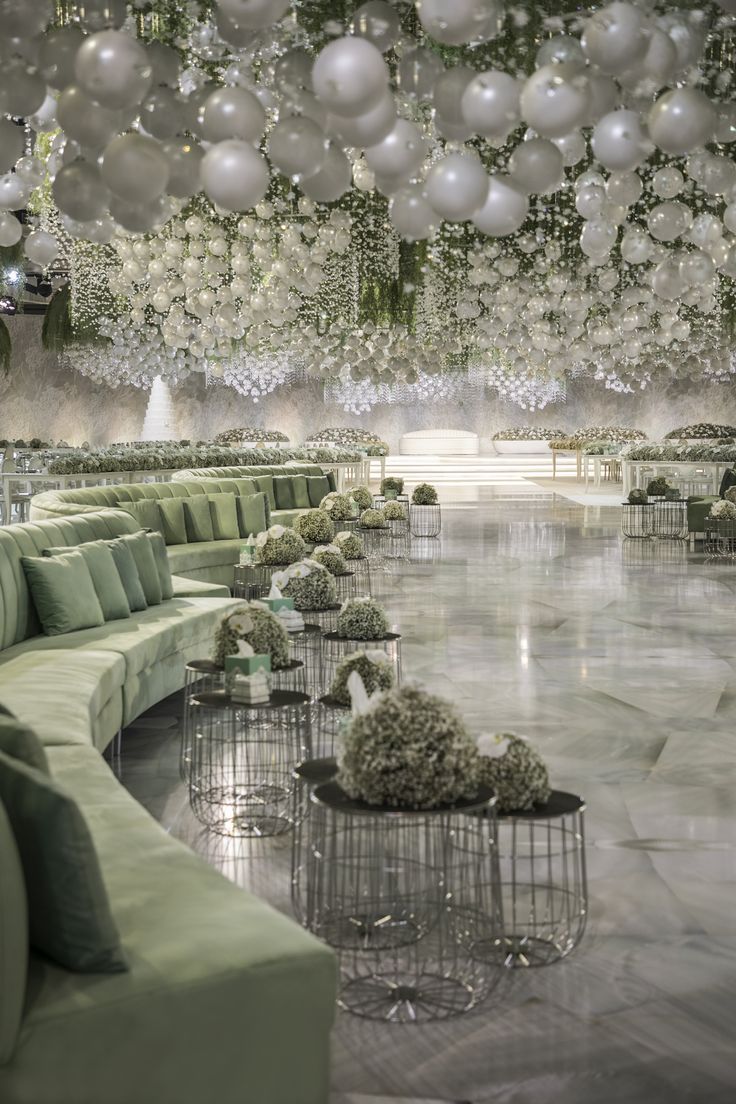 a room filled with lots of green couches and white balloons hanging from the ceiling