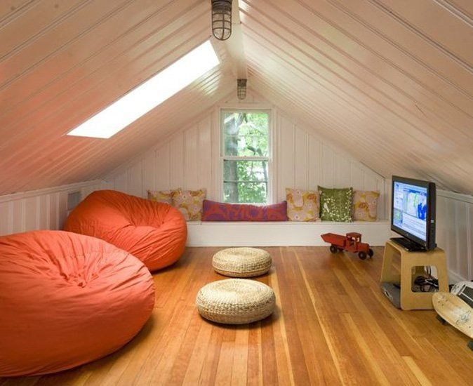 an attic bedroom with two bean bags on the floor and a television in the corner