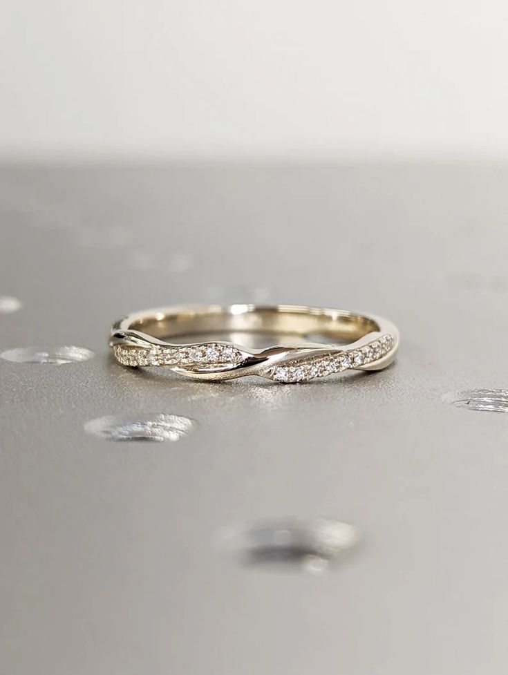 a gold wedding band with white diamonds on the side, sitting on top of a table