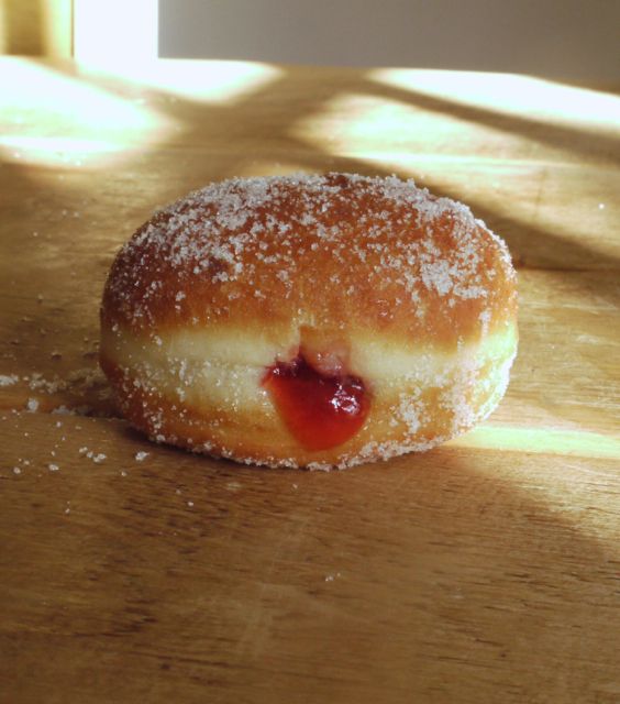 a donut with powdered sugar and jelly on it