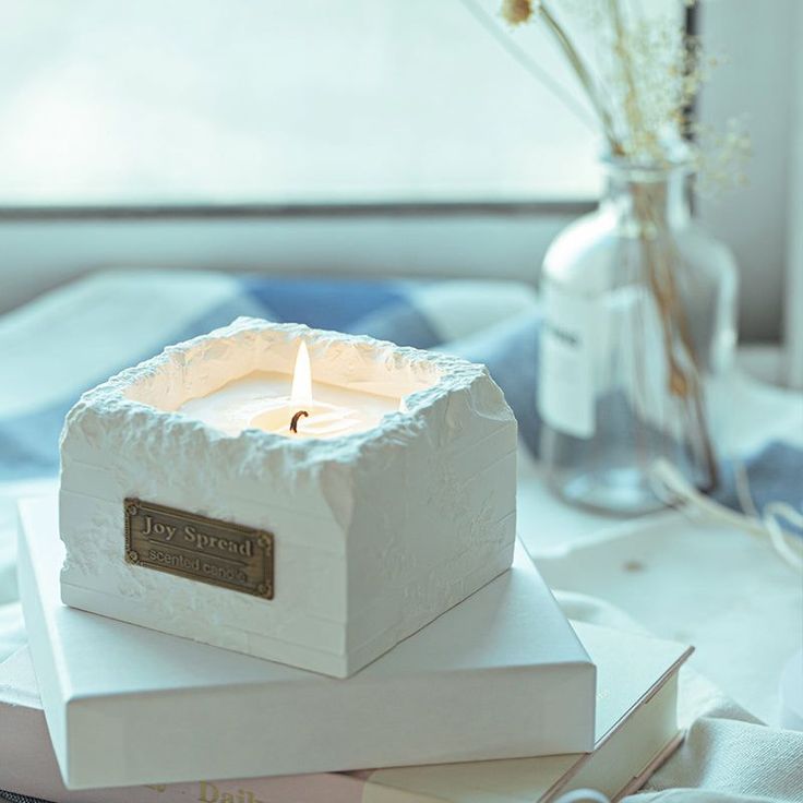 a white candle sitting on top of two books