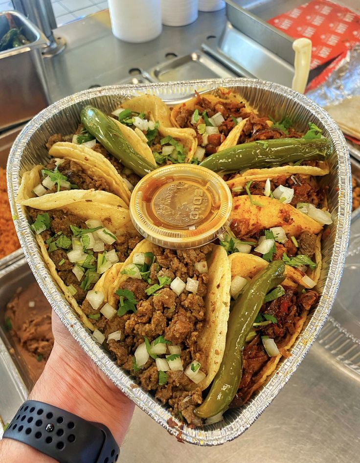 a heart shaped container filled with taco meat and green beans next to other food items