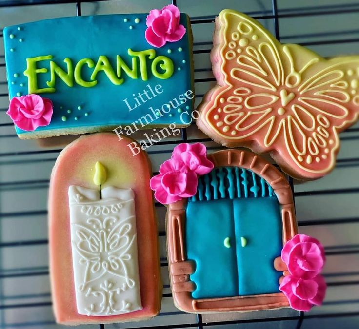 decorated cookies are displayed on a rack in front of a sign that says encanto