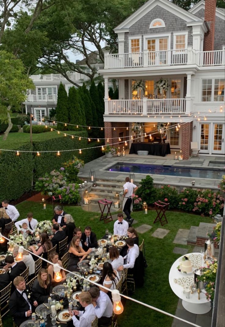 a group of people sitting at tables in front of a house