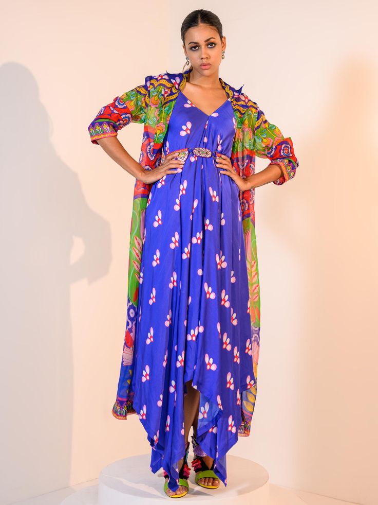 A three-piece Blue Indica Cowl Dress Set Paired with Jacket and Belt from the Juhi Bengani collection – Rang-Festive 2022. This gorgeous blue indica satin cowl dress is paired with a multicolored floral Veronica organza jacket. The bright and vibrant colors with floral print, heavy embroidery of mirror, beads, stones, and thread sequence work enhance this satin set. The indica blue cowl dress has a high-low hemline. This outfit is completed with an embroidered belt with symmetrical buckle. Mirror Beads, Organza Jacket, Cowl Dress, Satin Set, Embroidered Belt, Heavy Embroidery, Sequence Work, Dress Set, Three Piece