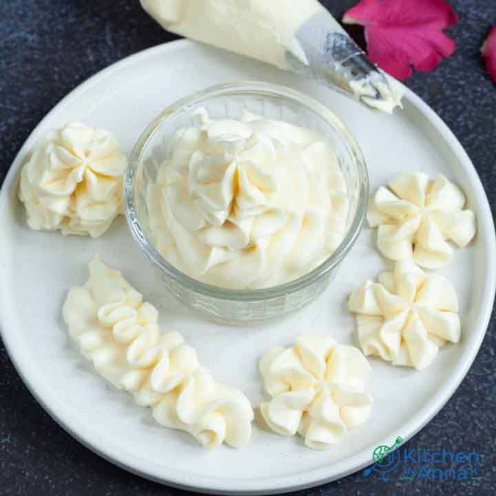 a white plate topped with whipped cream next to a knife and flower petals on a table