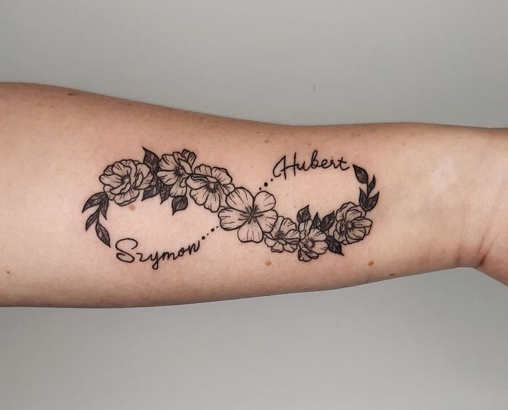 a woman's arm with flowers in the shape of a heart and an inscription on it