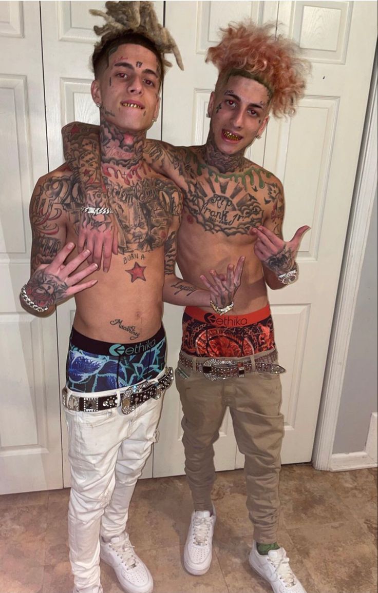 two men with tattoos and piercings standing next to each other in front of a door