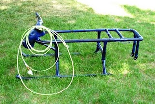 a hose is attached to the back end of a bike rack on some green grass