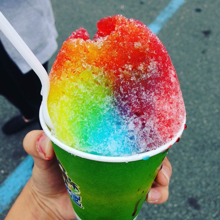 a person holding up a rainbow colored ice cream