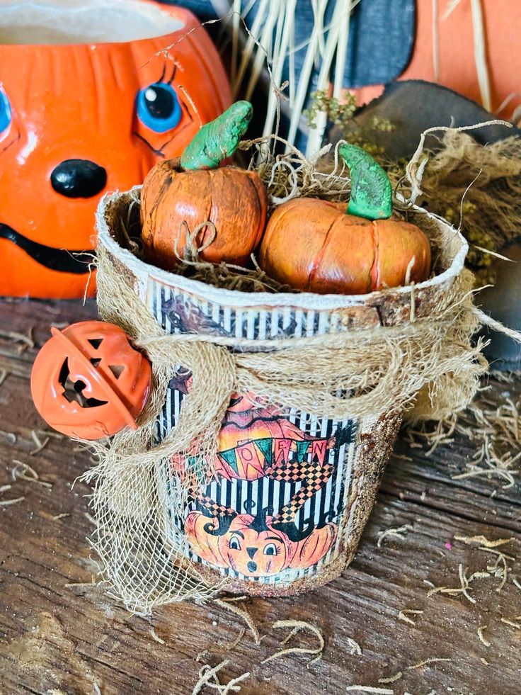 some pumpkins are sitting in a basket on a table next to other halloween decorations