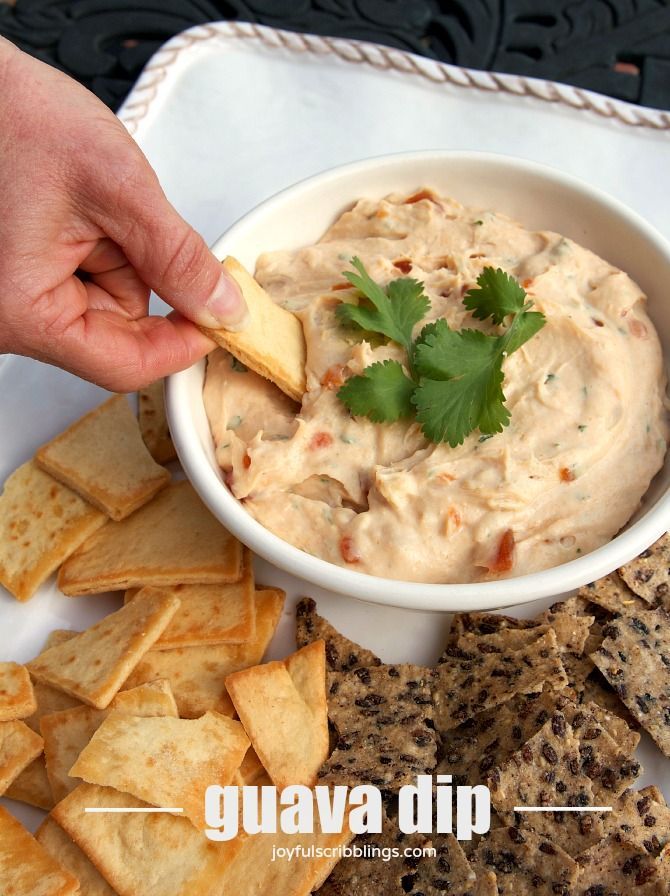 a bowl of dip surrounded by crackers and tortilla chips