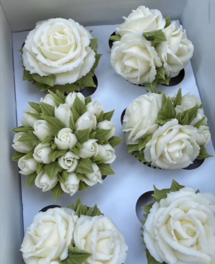 cupcakes decorated with white flowers in a box