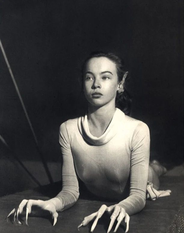 a woman sitting on the floor with her hands in front of her face and arms stretched out